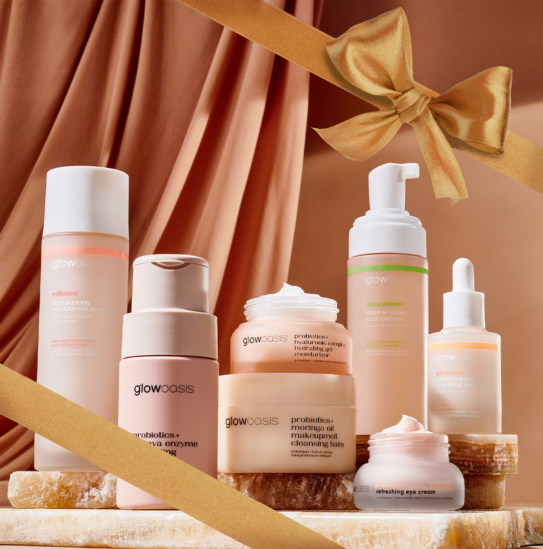 Assortment of glowoasis vegan probiotic skincare products laid out in front of a curtain with holiday ribbons and bow.