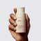 Hand holding up glowoasis vegan probiotics + papaya enzyme exfoliating powder.