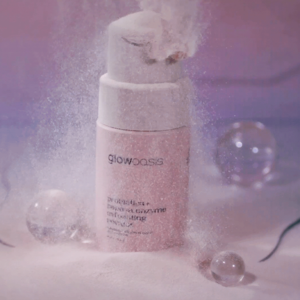 glowoasis vegan probiotics + papaya enzyme exfoliator’s powder falling down onto its sustainable skincare packaging.