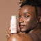 Male holding glowoasis vegan probiotics + papaya enzyme exfoliating powder above his shoulder.