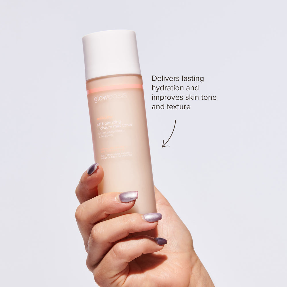 Hand holding glowoasis vegan probiotic milkdew pH balancing toner against a white background.