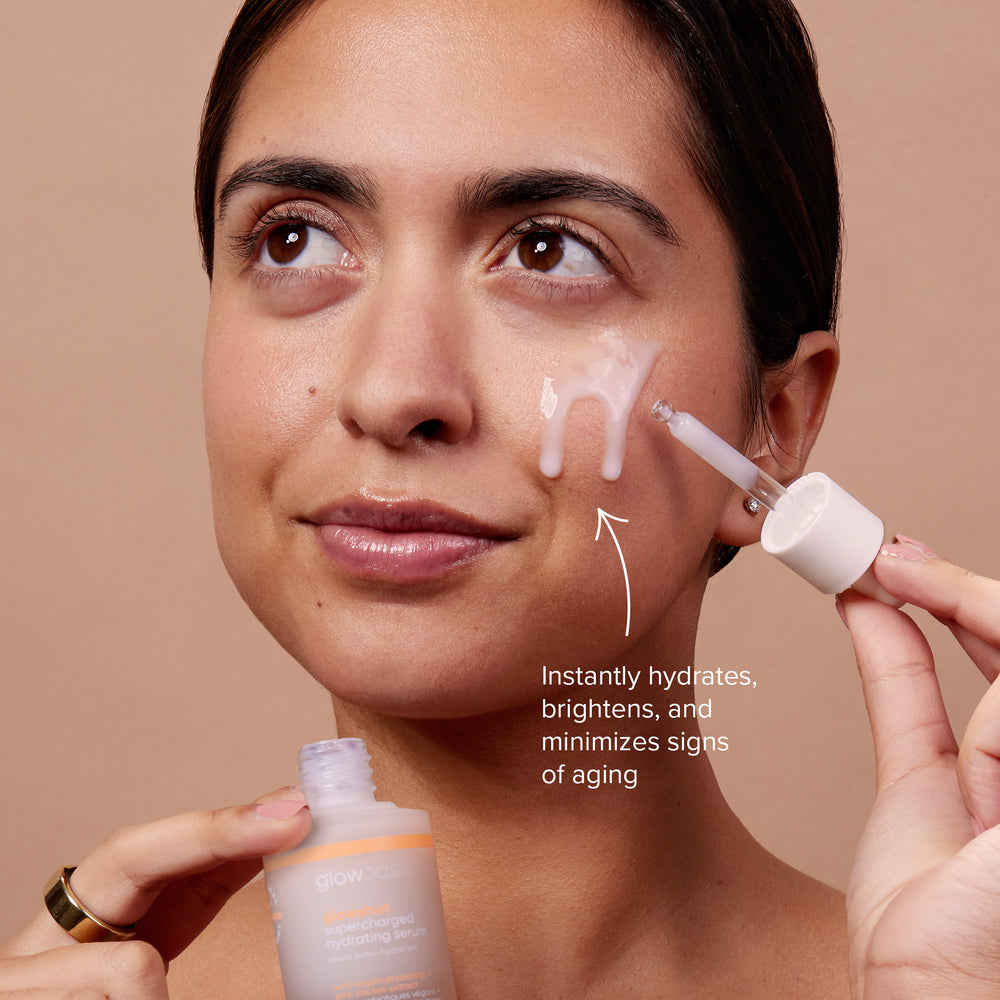 Female with glowoasis vegan probiotic glowshot hydrating serum dripping down her cheek while holding its bottle.