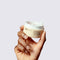 Hand holding glowoasis vegan probiotics moringa oil makeupmelt cleansing balm with its included spatula for application.