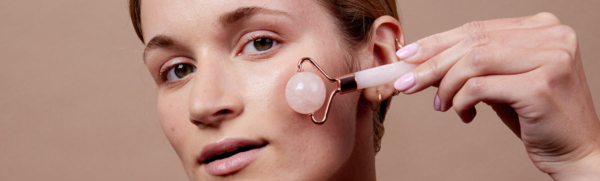 image of woman using rose quartz face roller to massage her cheek area