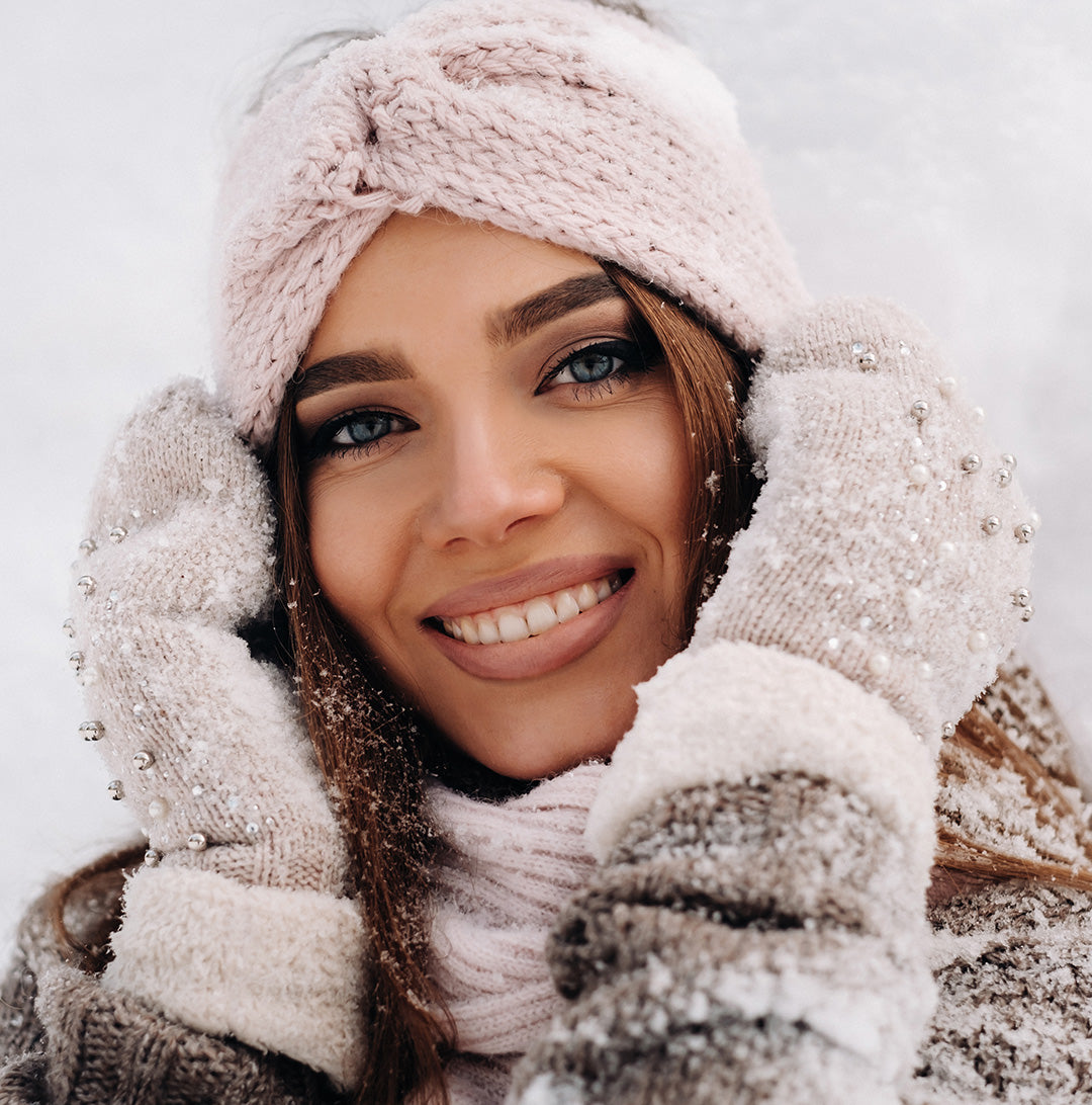 Happy woman bundled up in the snow with glowing, healthy skin thanks to vegan probiotic skincare.