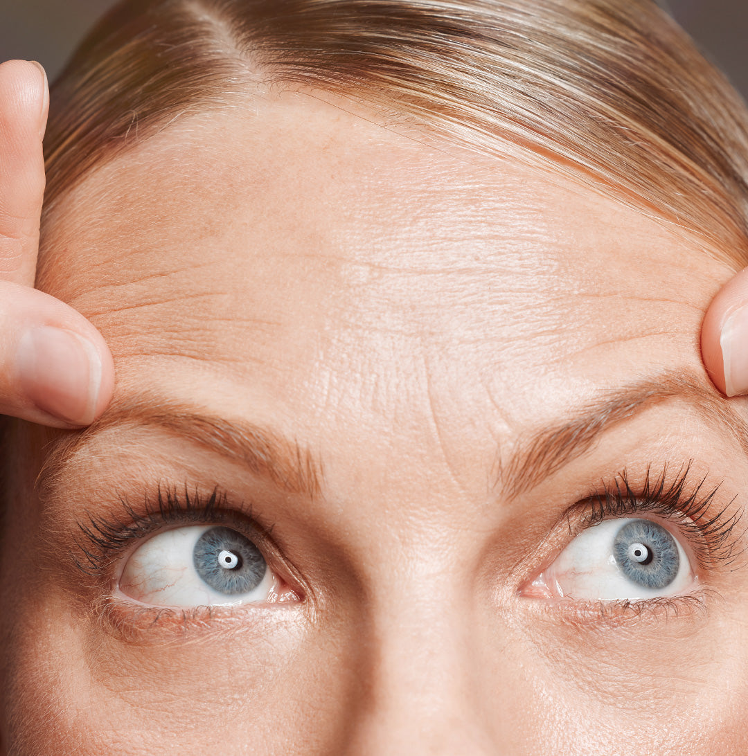 Female analyzing the fine lines and wrinkles on her forehead
