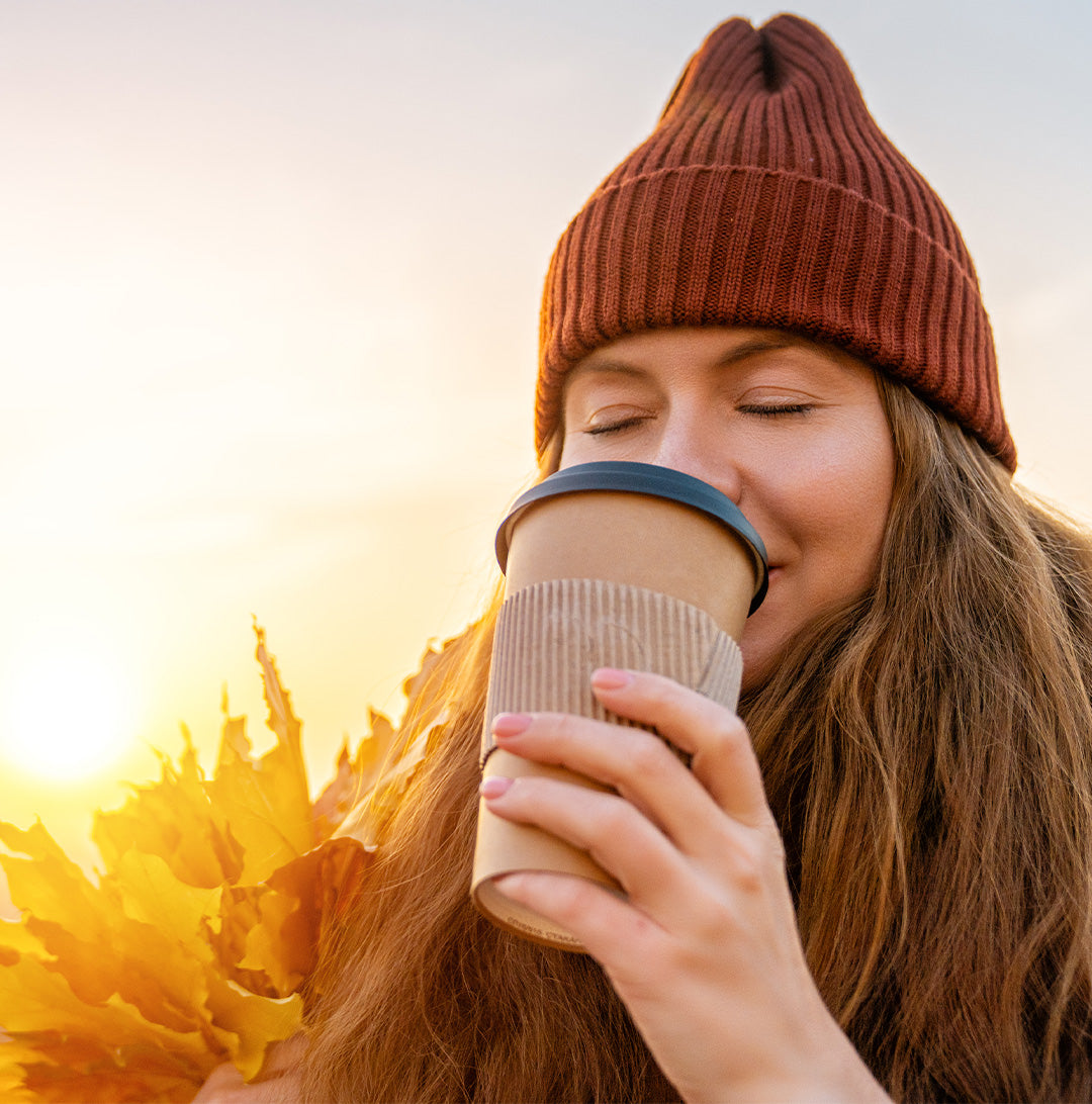 Female with healthy skin sipping on hot beverage on a chilly, but sunny day.