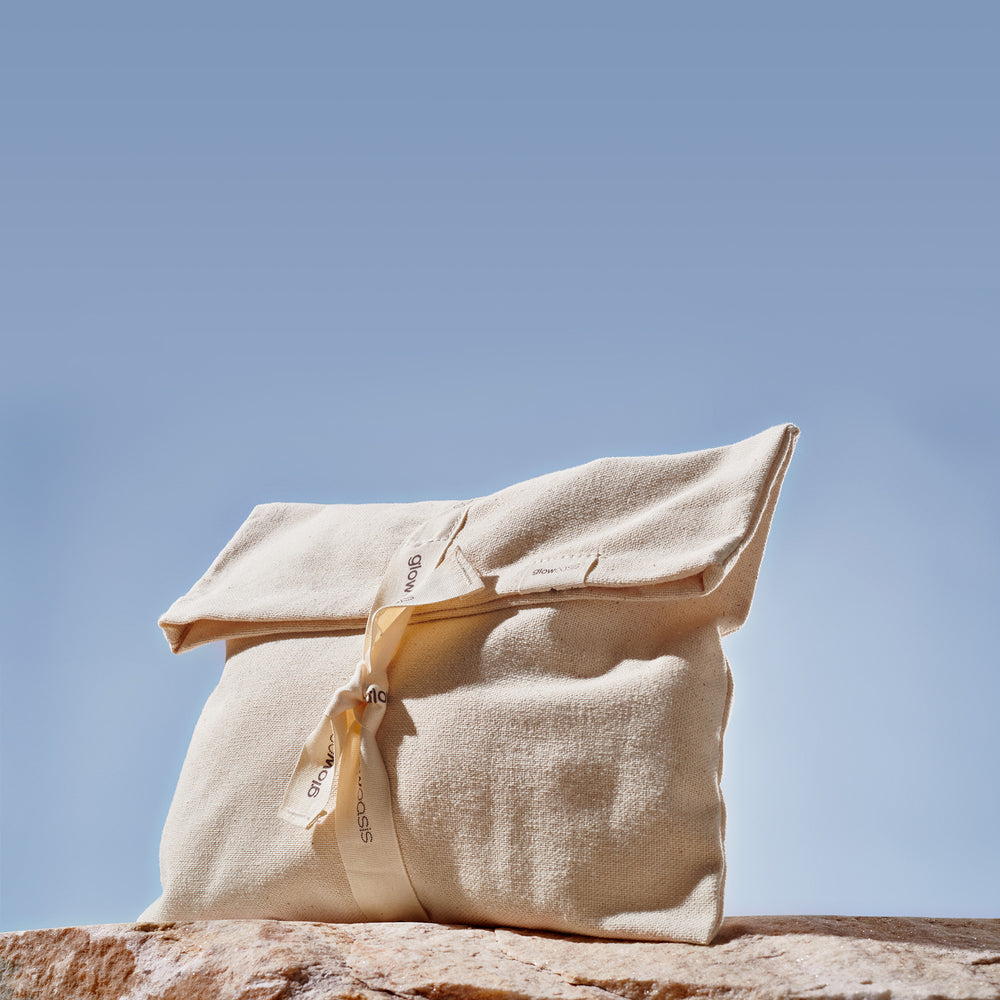 glowoasis foldover canvas pouch for skincare storage on top of a rock in the outdoors.