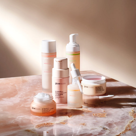 glowoasis ultimate oasis full skincare set on a tabletop, featuring facial cleansers, enzyme exfoliant, balancing toner, hydrating serum, and hydrating gel moisturizer.