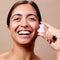 Smiling female model holding up glowoasis rose quartz eye massager.