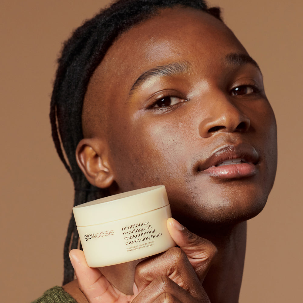 Male model holding the glowoasis vegan probiotics moringa oil makeupmelt cleansing balm container showing makeup removal.
